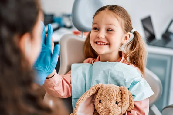 A young girl giving a high-five in a dental office during a pediatric appointment.